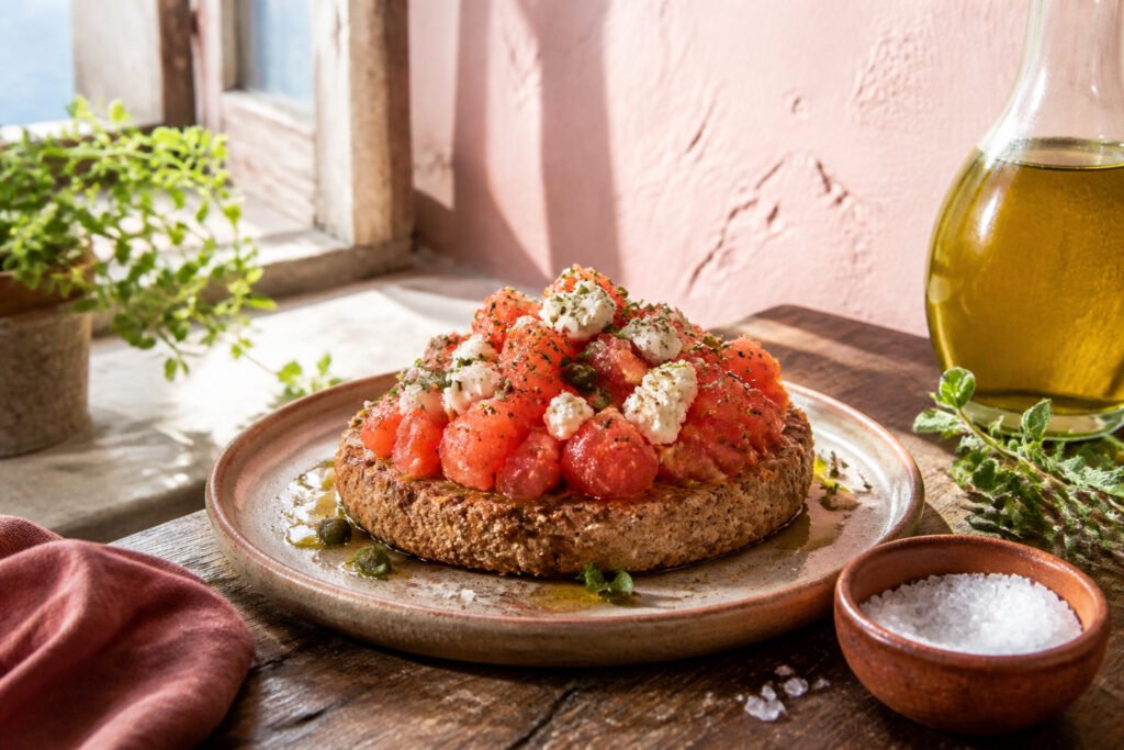 A serving of Cretan dakos with tomato mixture and cheese on top.
