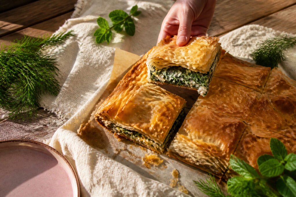 A golden-brown spanakopita with flaky pastry and green filling.
