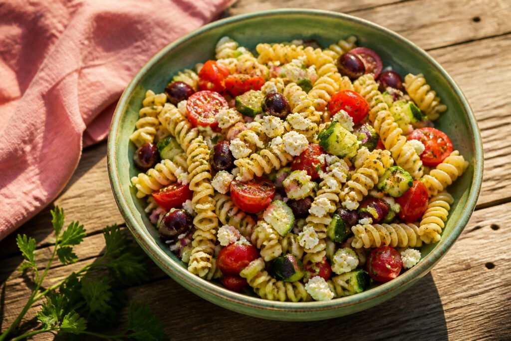 A bowl of Greek pasta salad with colorful ingredients.